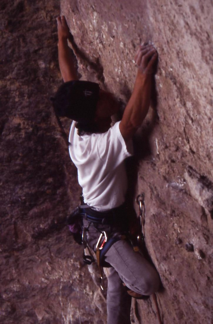 Back to the camera, arms up on the red rock